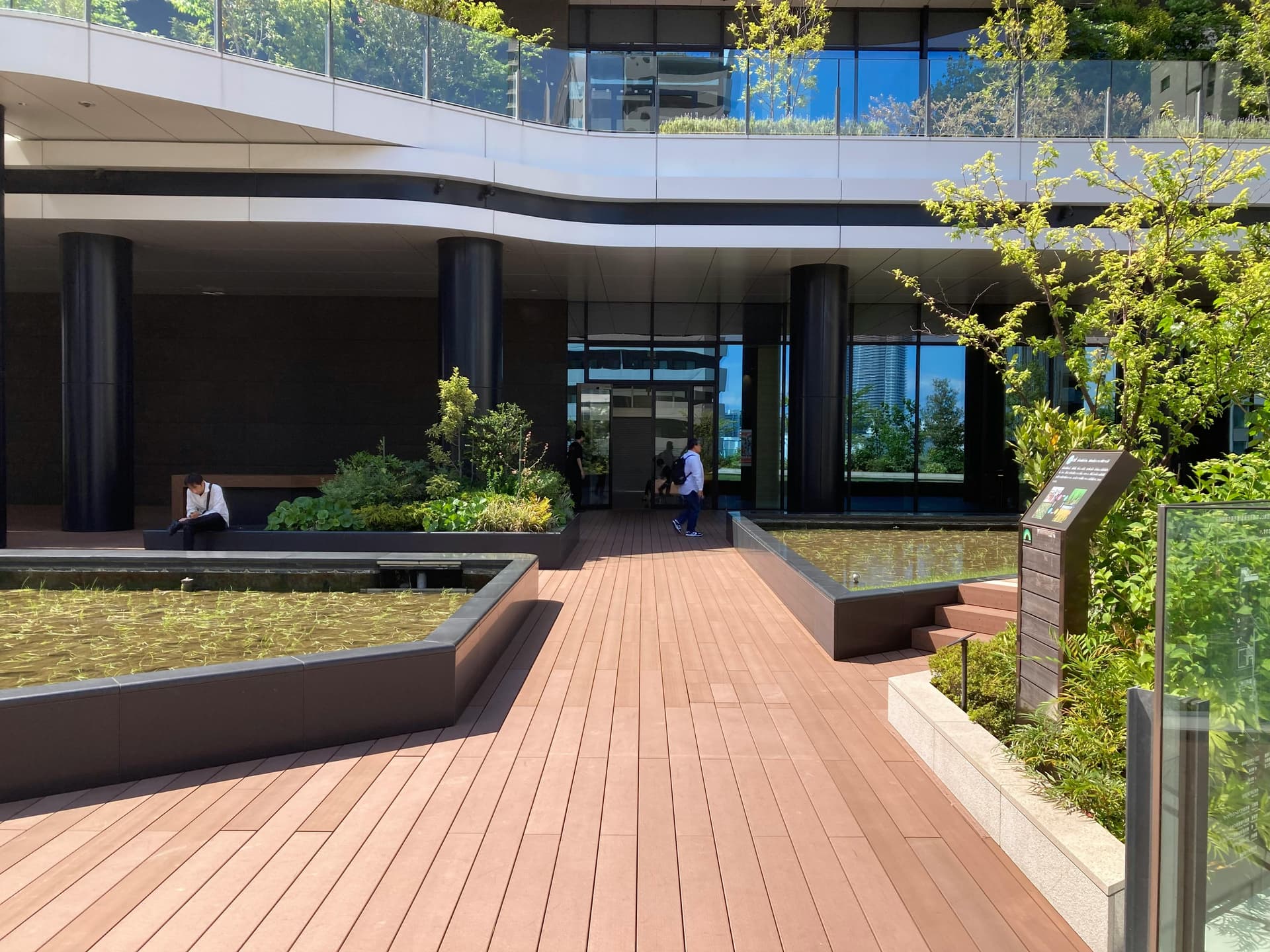 Modern Tokyo building courtyard with water features, wooden decking, and integrated greenery