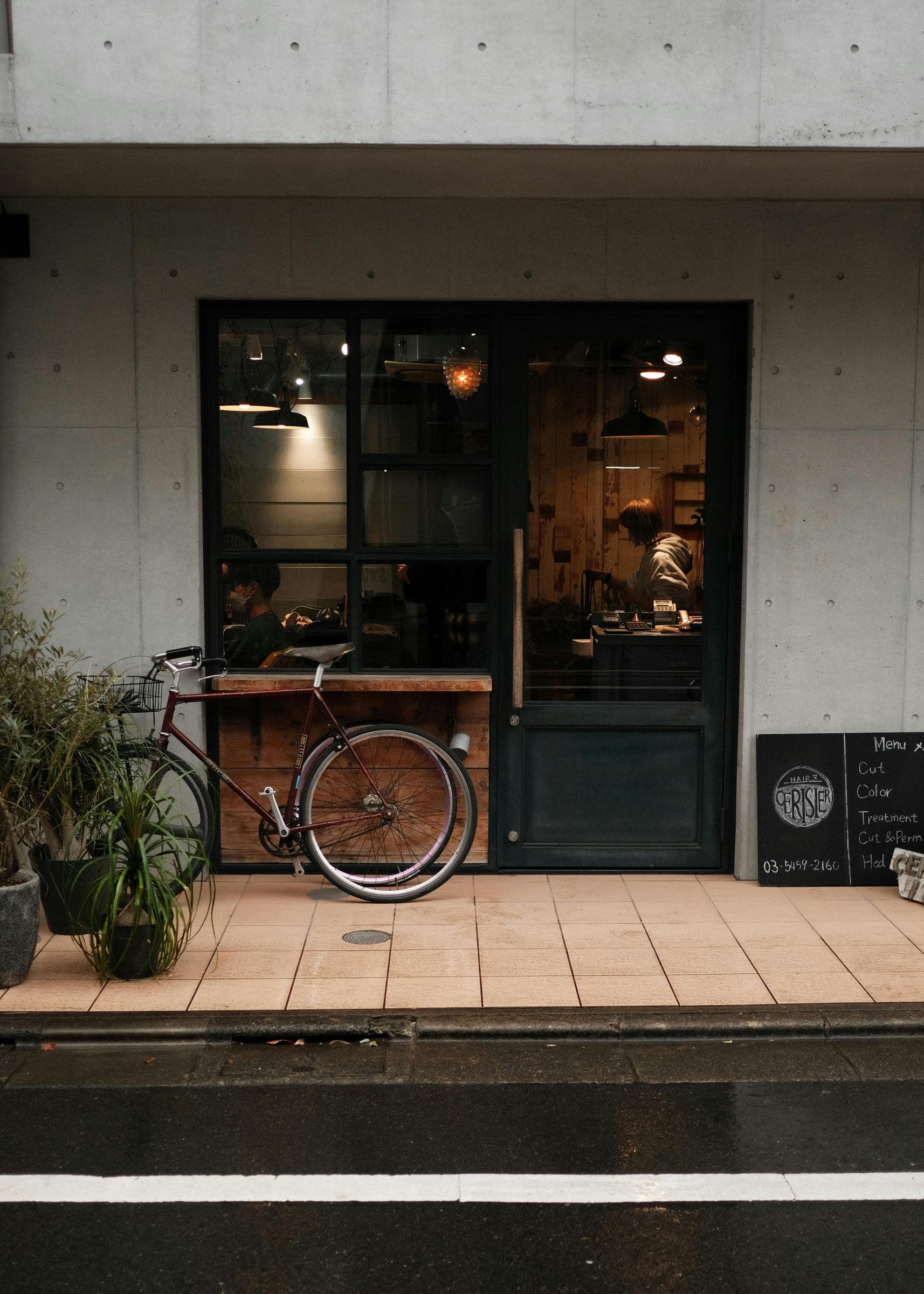 Quiet Tokyo cafe storefront with bicycle on a rainy side street
