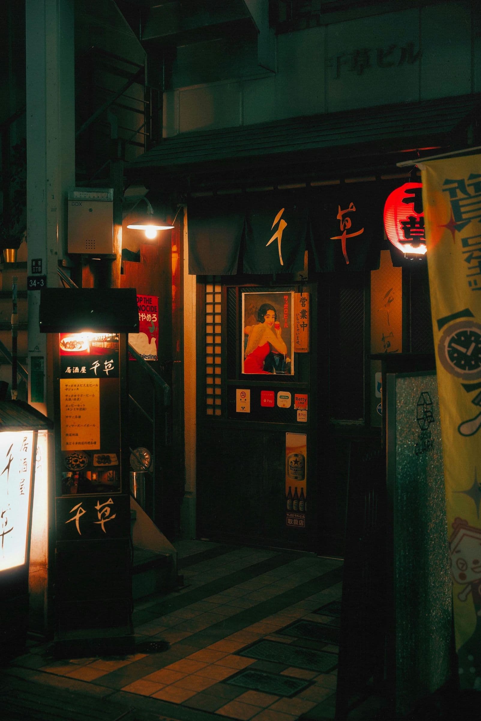 Hidden izakaya entrance with noren curtains and glowing red lantern at night