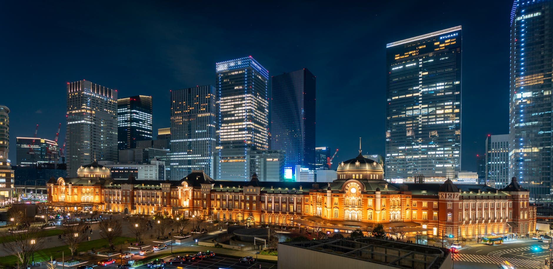 Tokyo Station at night with skyscrapers towering behind it