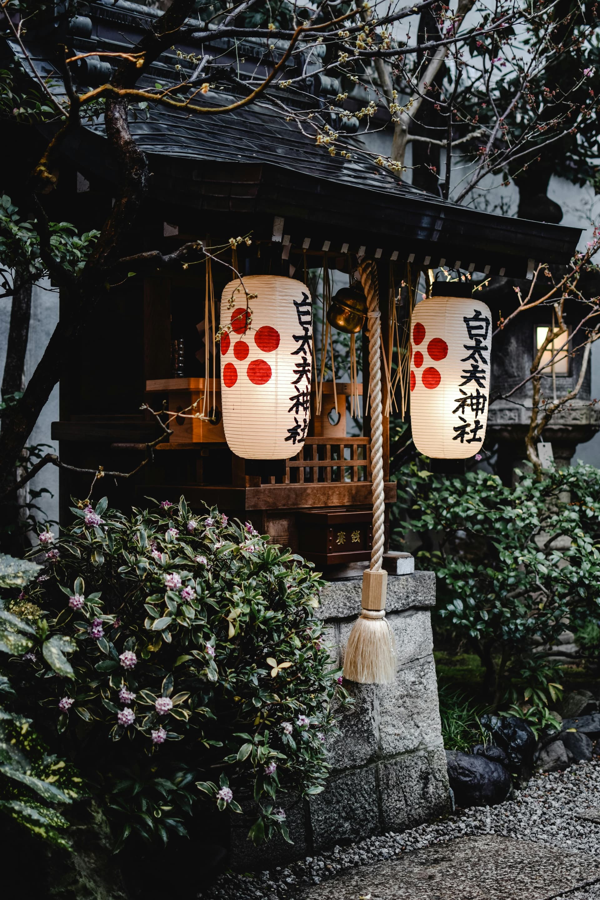 Traditional Japanese shrine lanterns glowing at dusk in a quiet suburban neighborhood