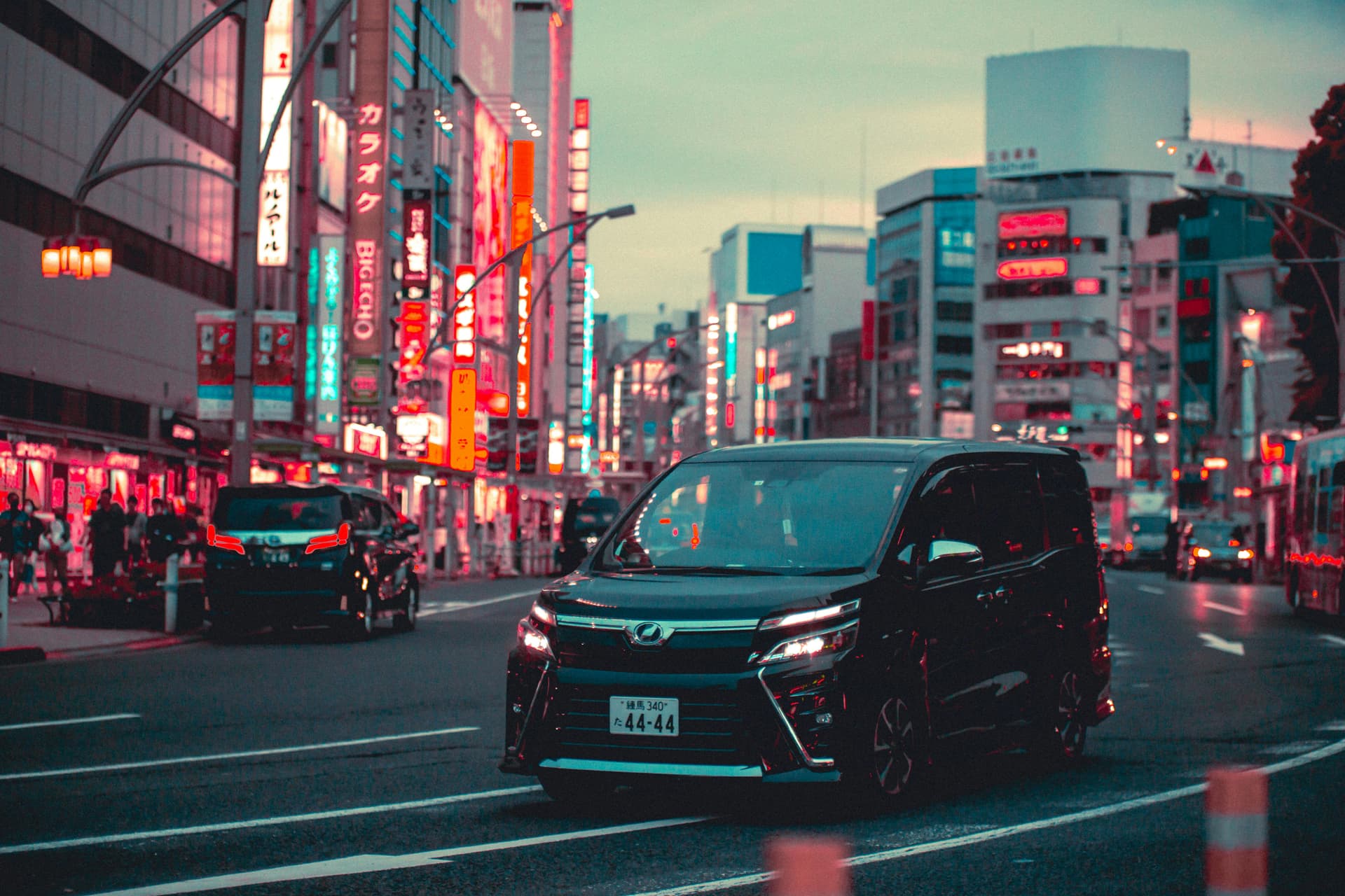 Private Toyota minivan driving through neon-lit Tokyo streets at night