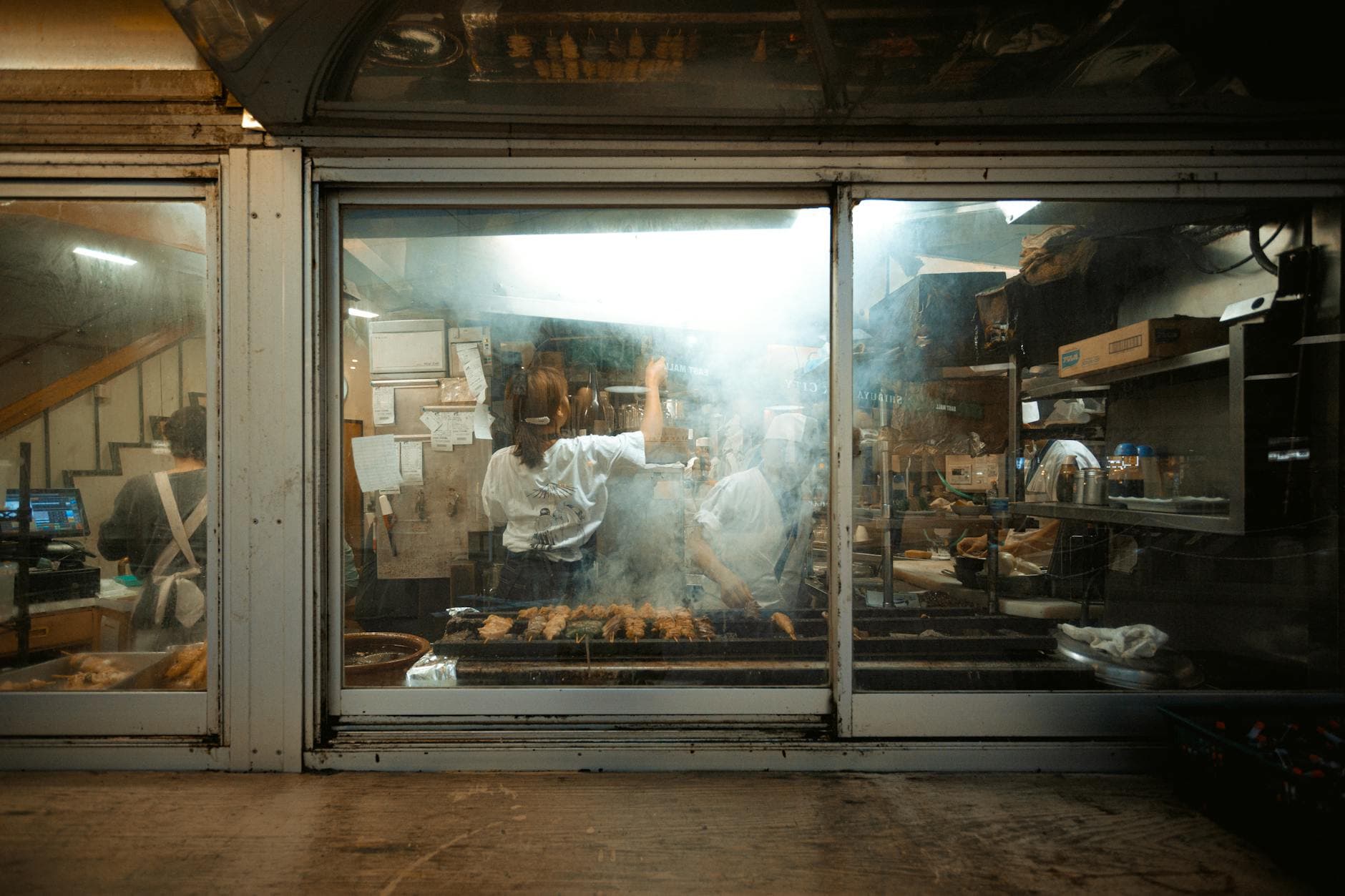 Chefs working over smoke and flames at a Tokyo street food counter