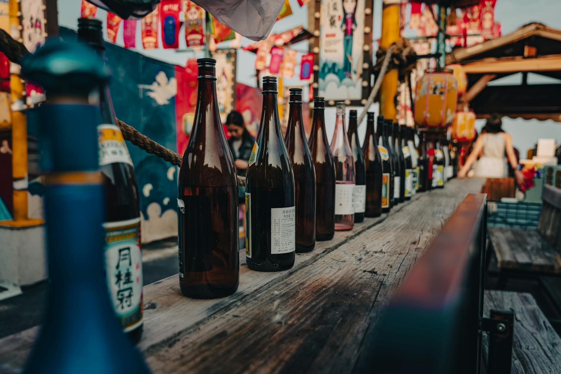 Row of sake bottles on wooden table at an outdoor Japanese festival