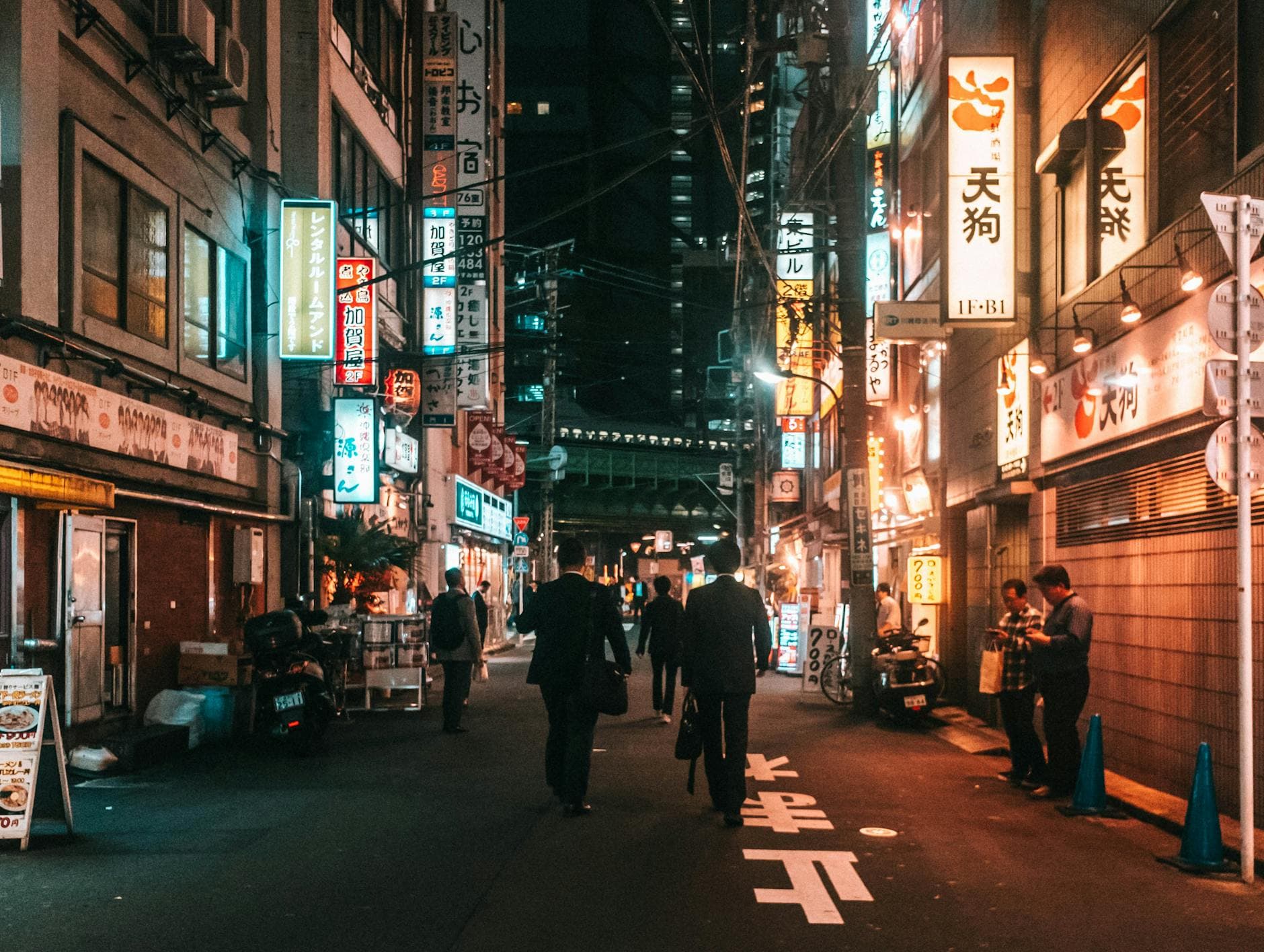 People walking past illuminated signs on Tokyo streets at night