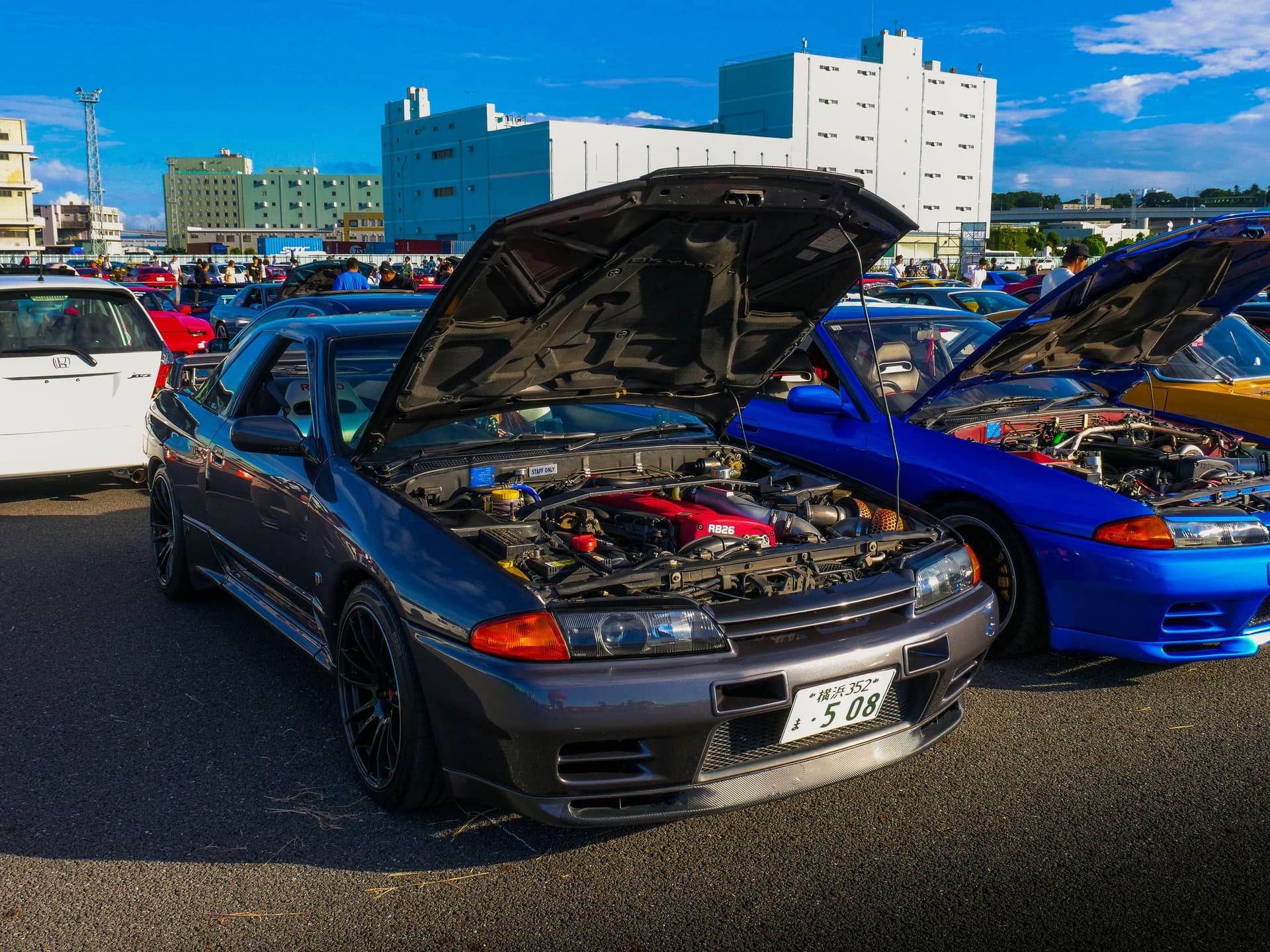 Nissan Skyline GT-R R32 with hood open showing RB26 engine at a car meet