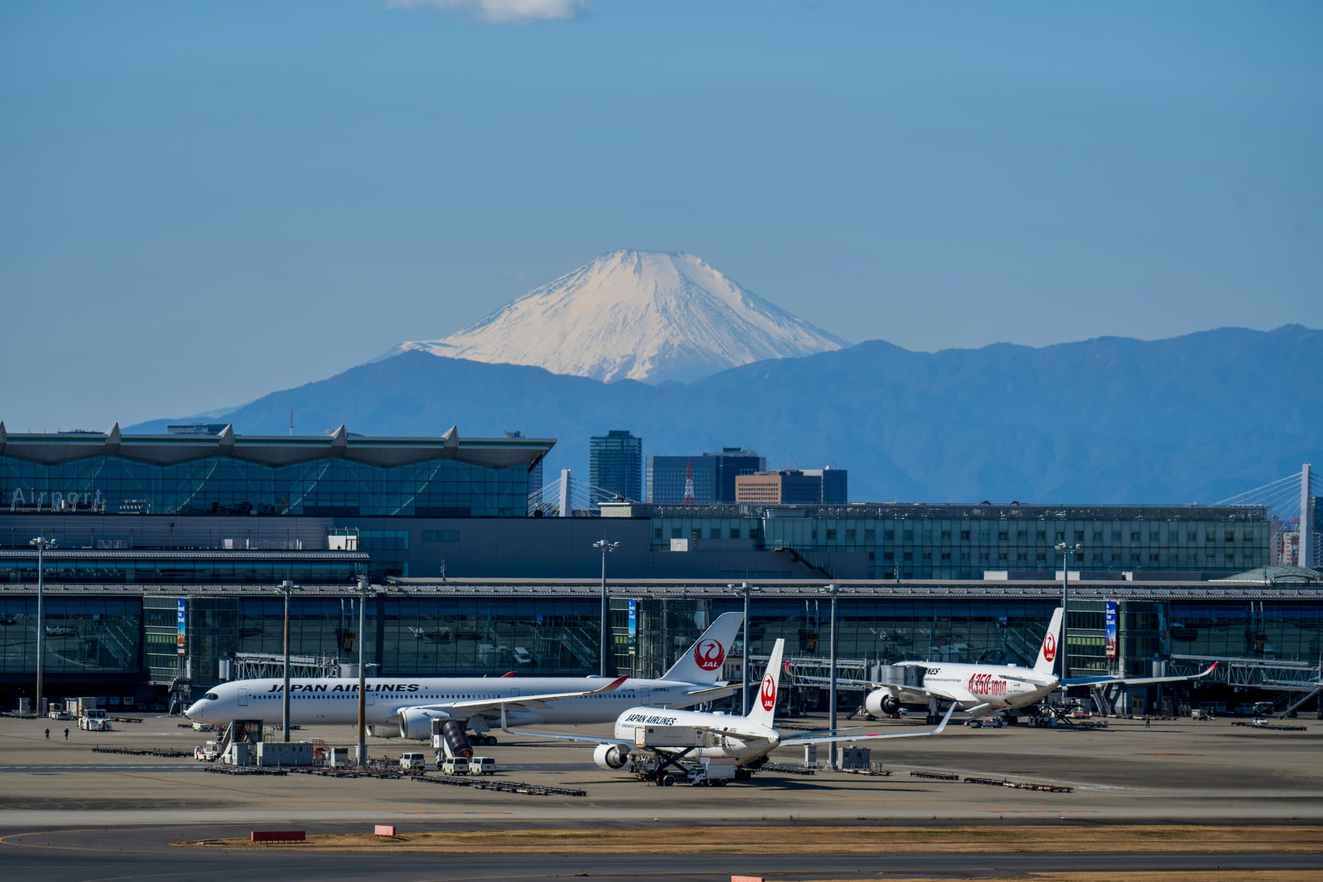 Mount Fuji rising behind Haneda Airport with Japan Airlines planes on the tarmac