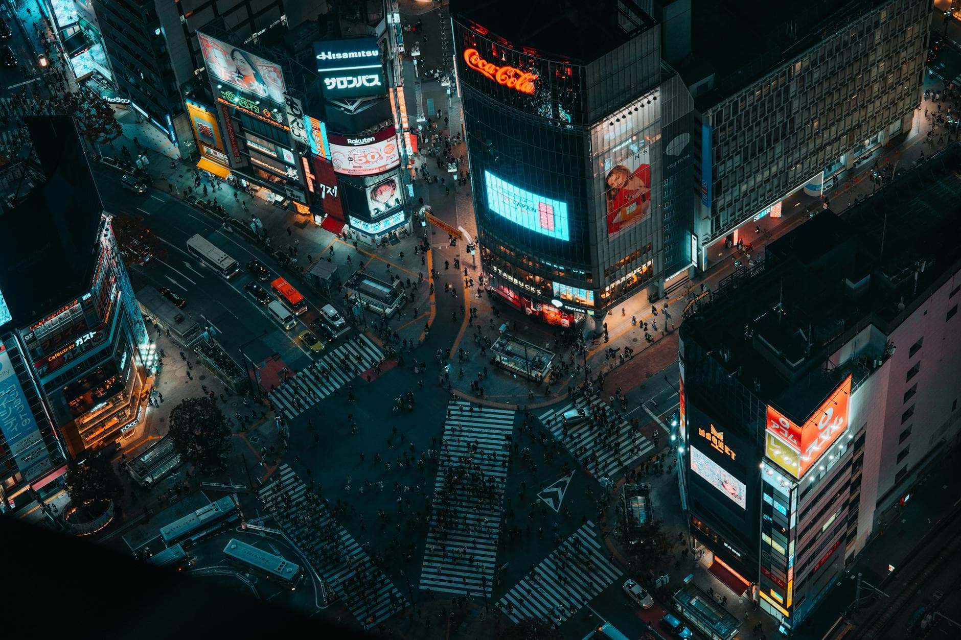 Shibuya Crossing from above at night with illuminated billboards and crowds