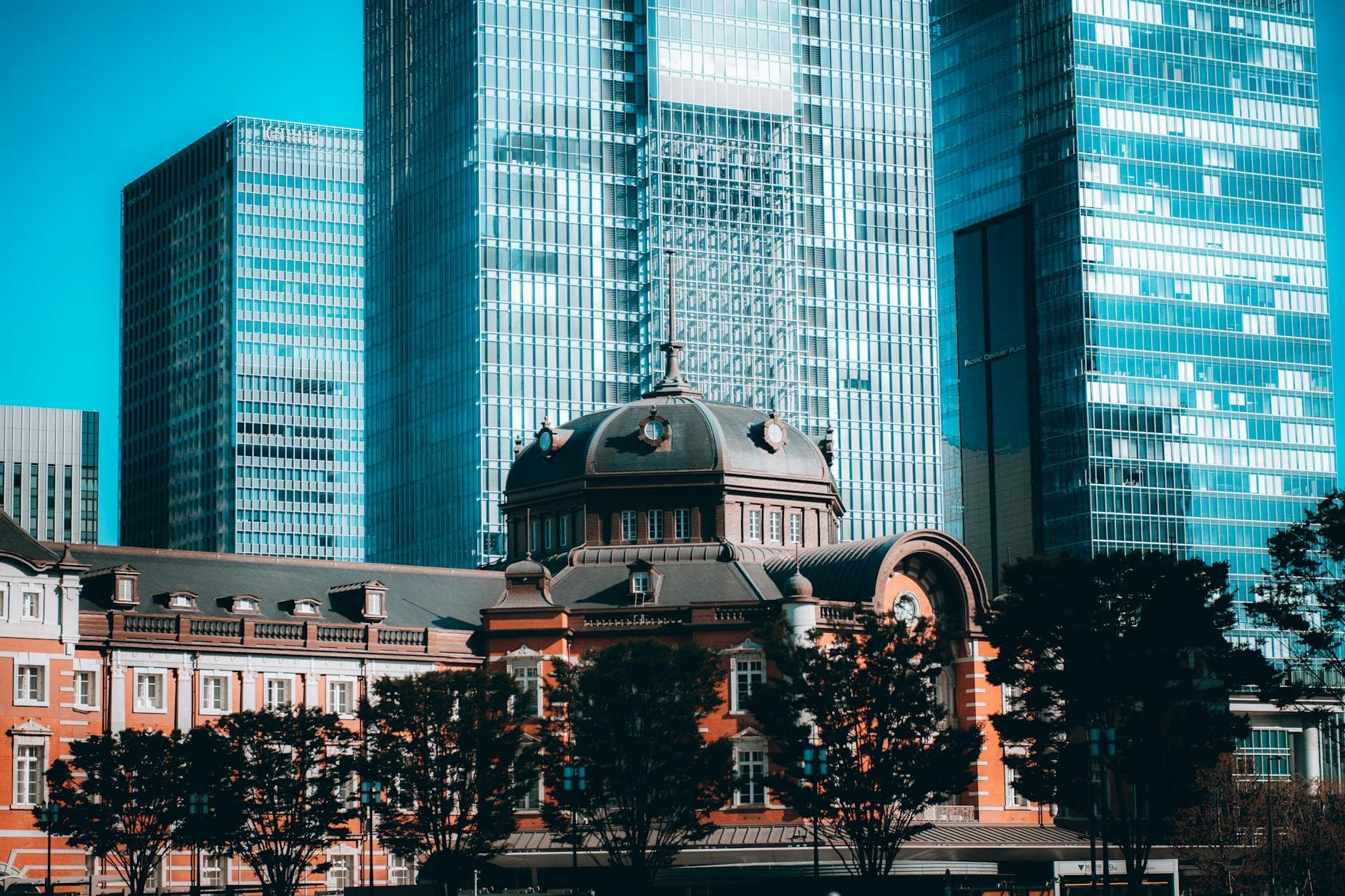 Historic Tokyo Station red brick building framed by modern glass towers