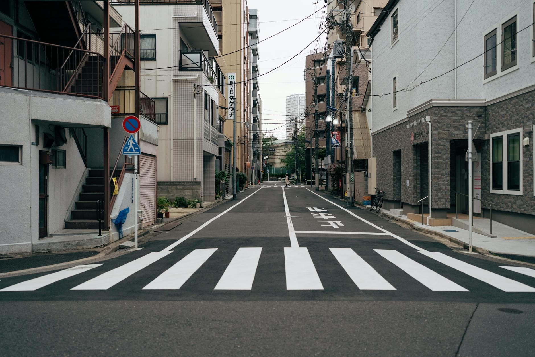 Quiet Tokyo residential street with crosswalk and low-rise urban architecture