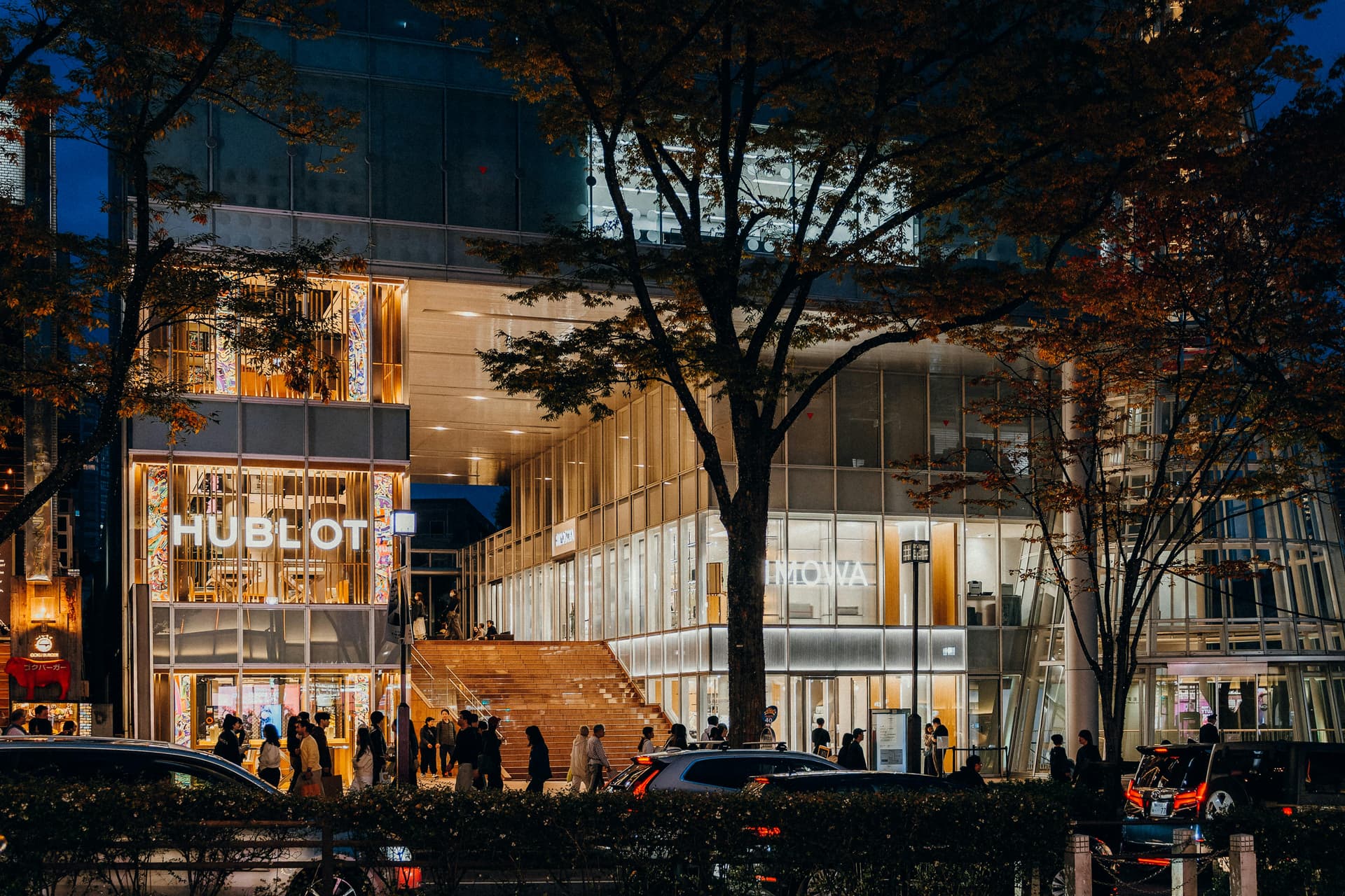 Hublot and Rimowa luxury storefronts illuminated at night on Omotesando avenue
