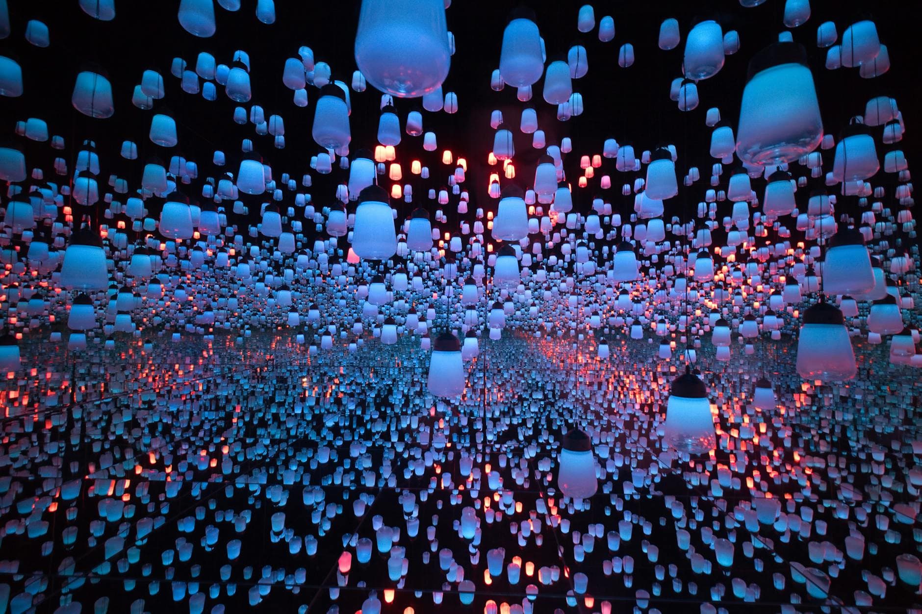 Glowing lanterns suspended in mirrored room at teamLab Planets Tokyo