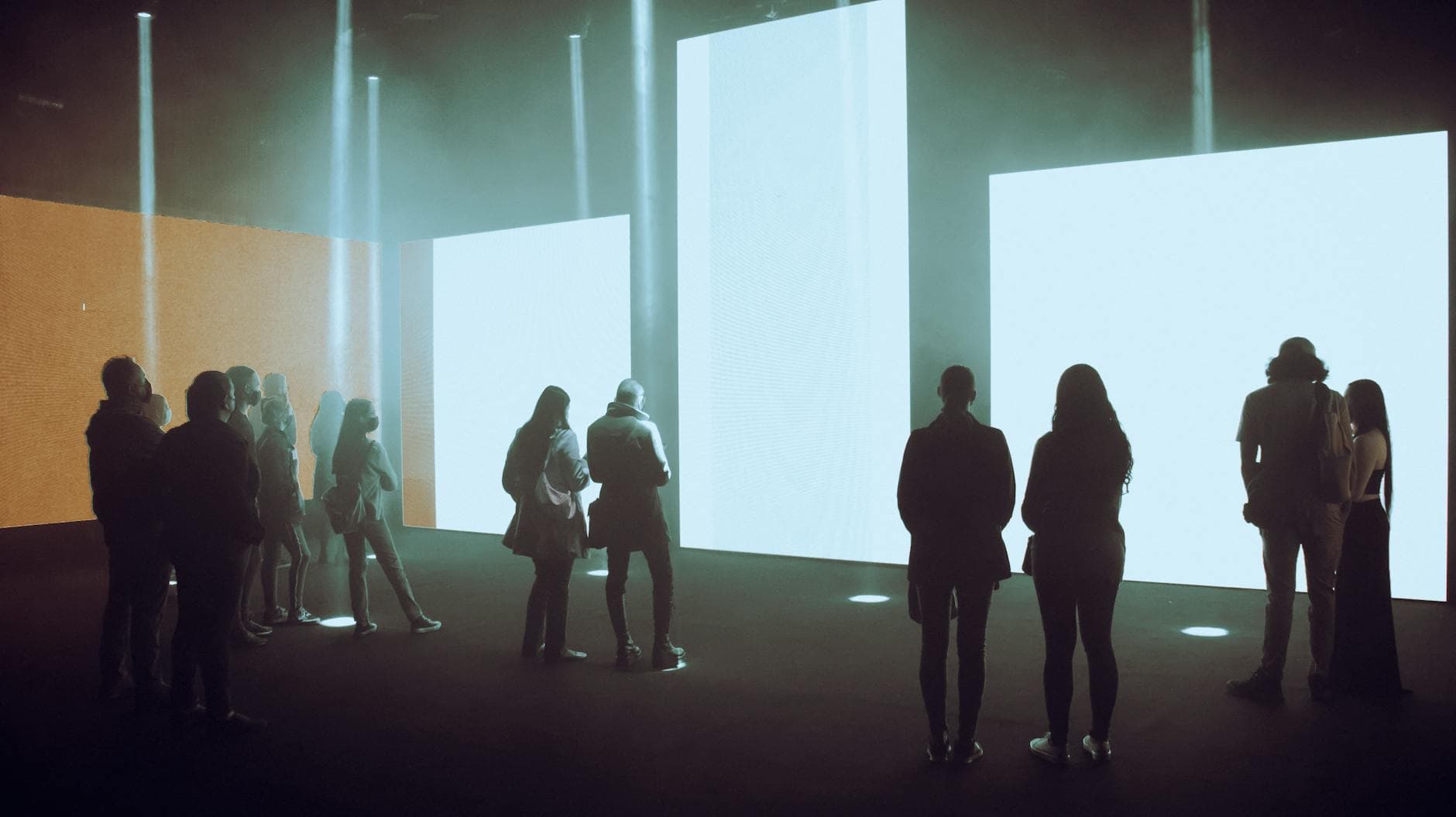 Visitors silhouetted against illuminated digital art installation
