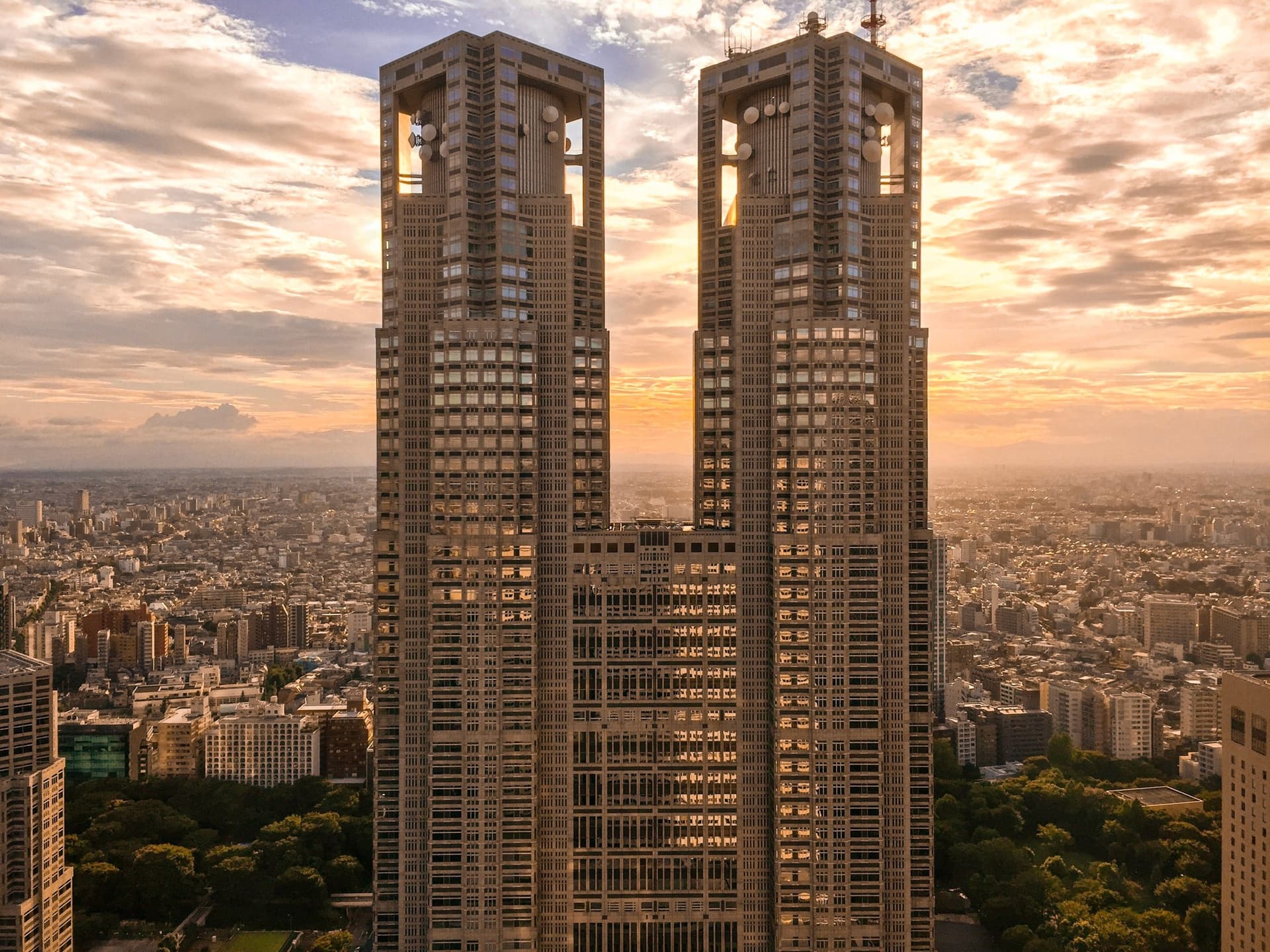 Tokyo Metropolitan Government Building towers at golden-hour sunset with city panorama