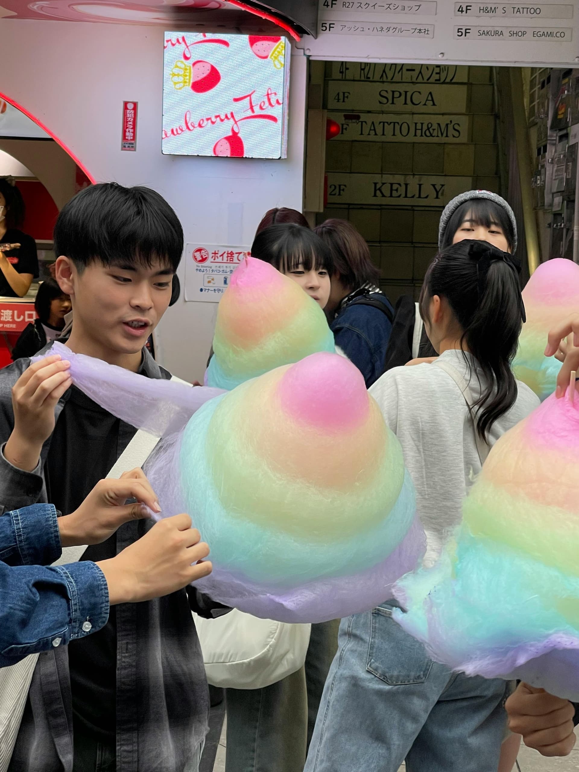 Young people holding giant pastel cotton candy on a busy Harajuku street