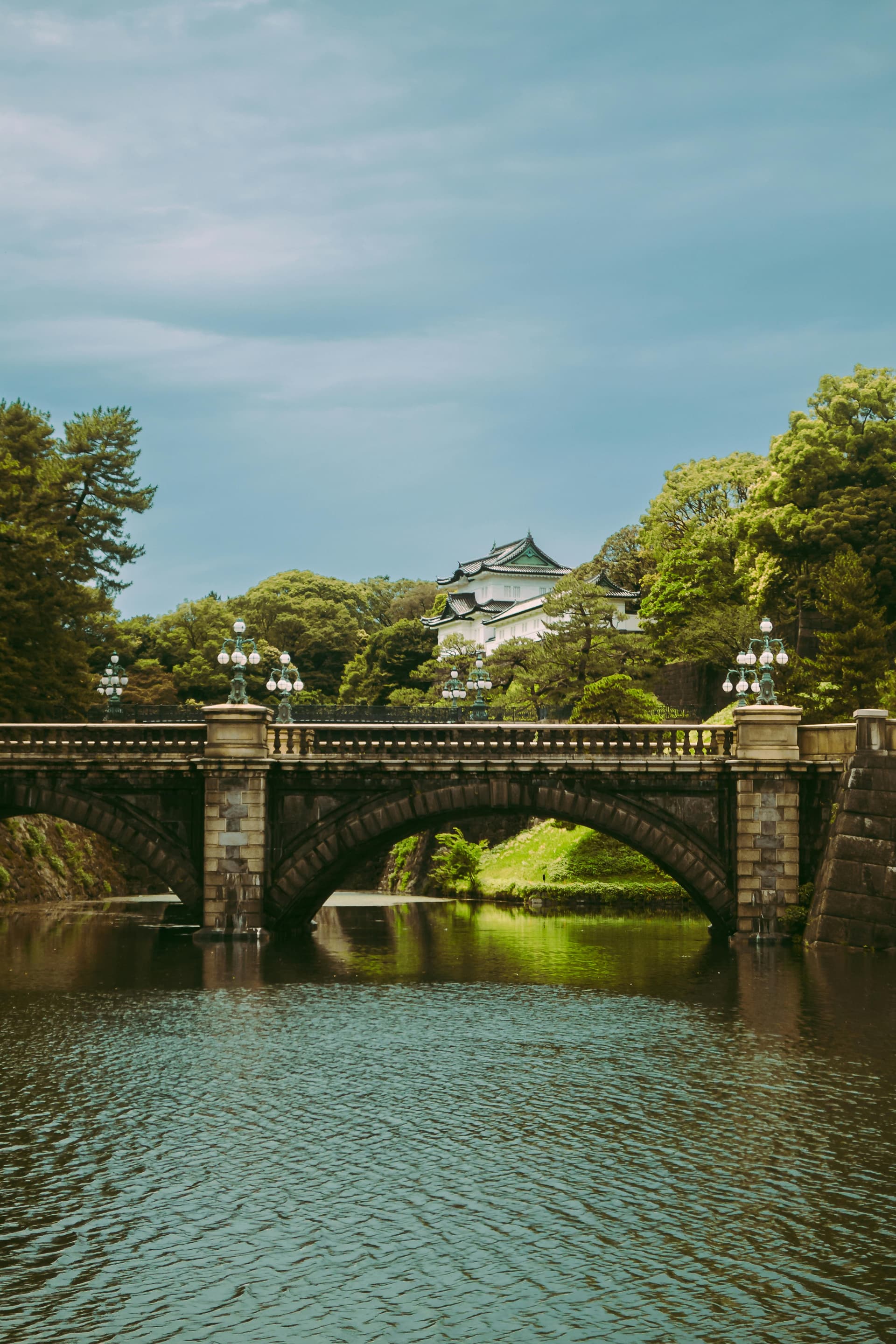 Stone bridge over moat leading to Imperial Palace with castle tower in the background