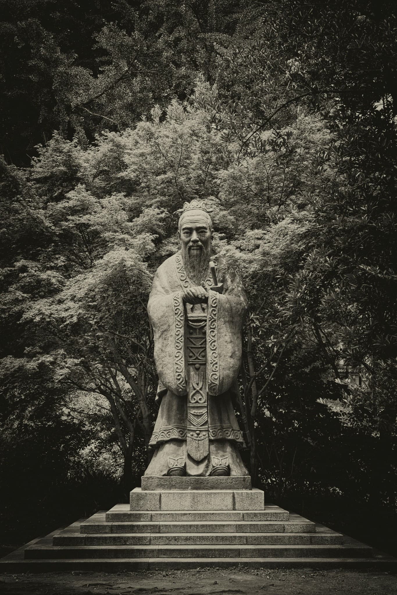 Stone statue in a wooded shrine garden surrounded by greenery