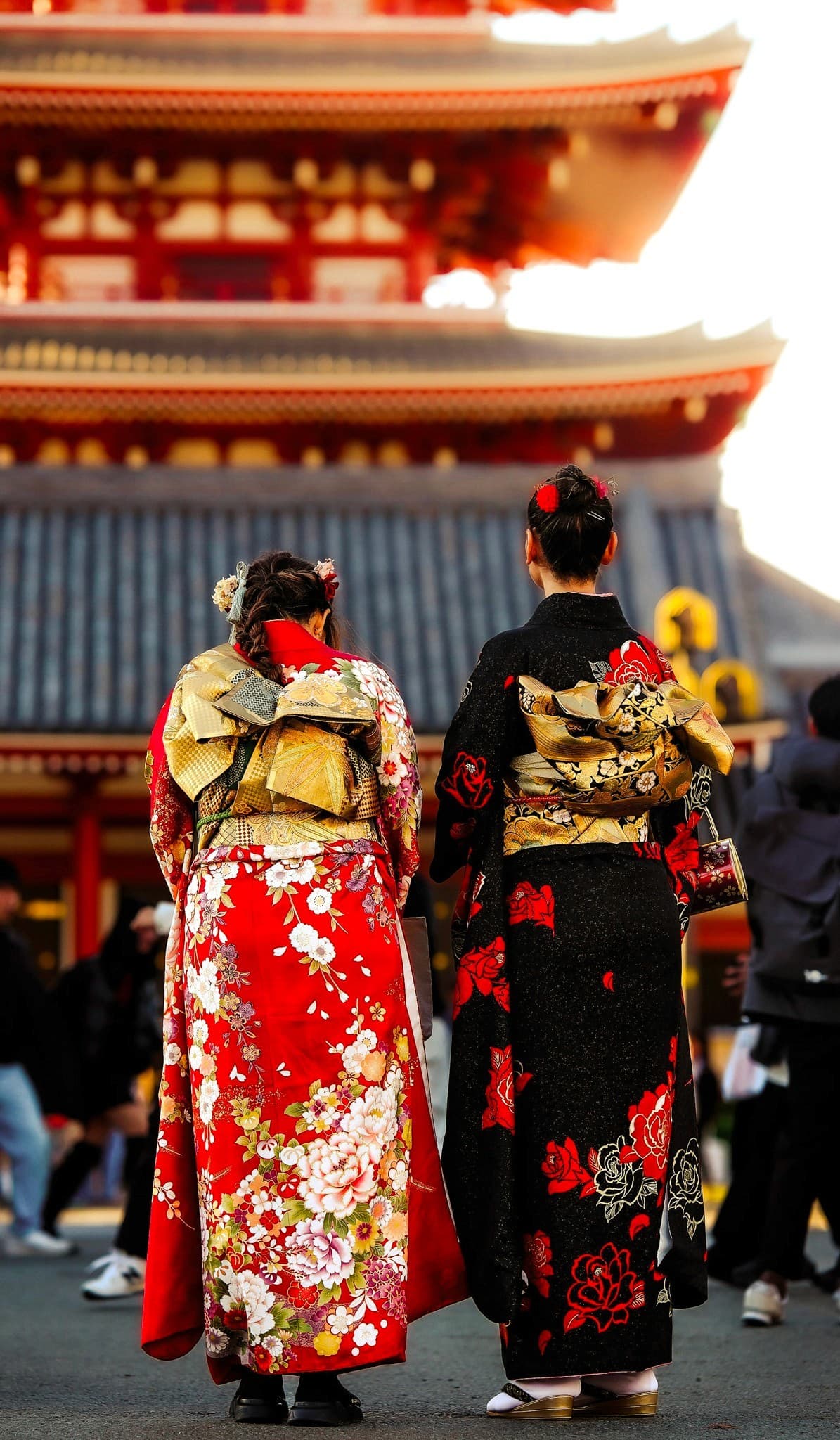 Two women in vibrant furisode kimono facing Senso-ji pagoda