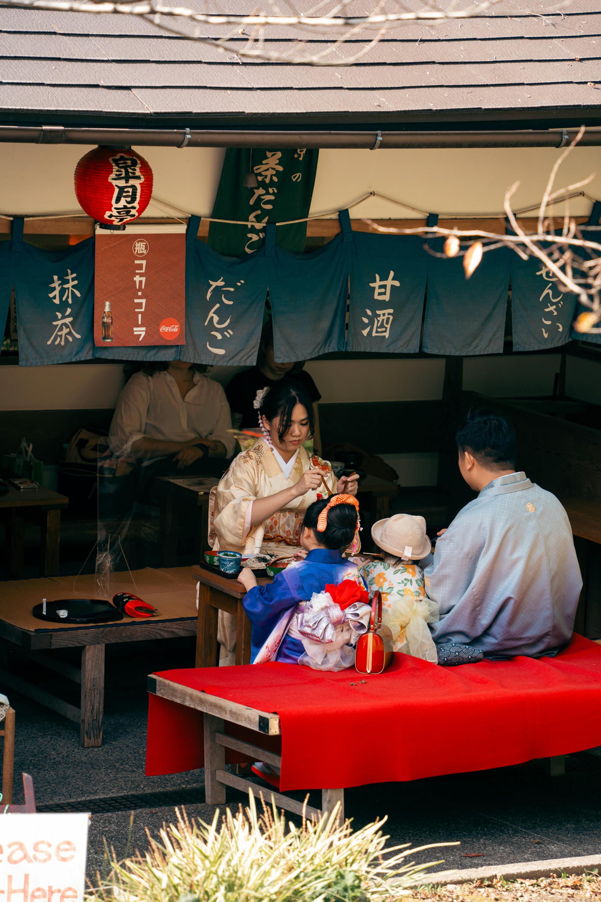 Family in kimono at a dango stall - guide facilitates the experience