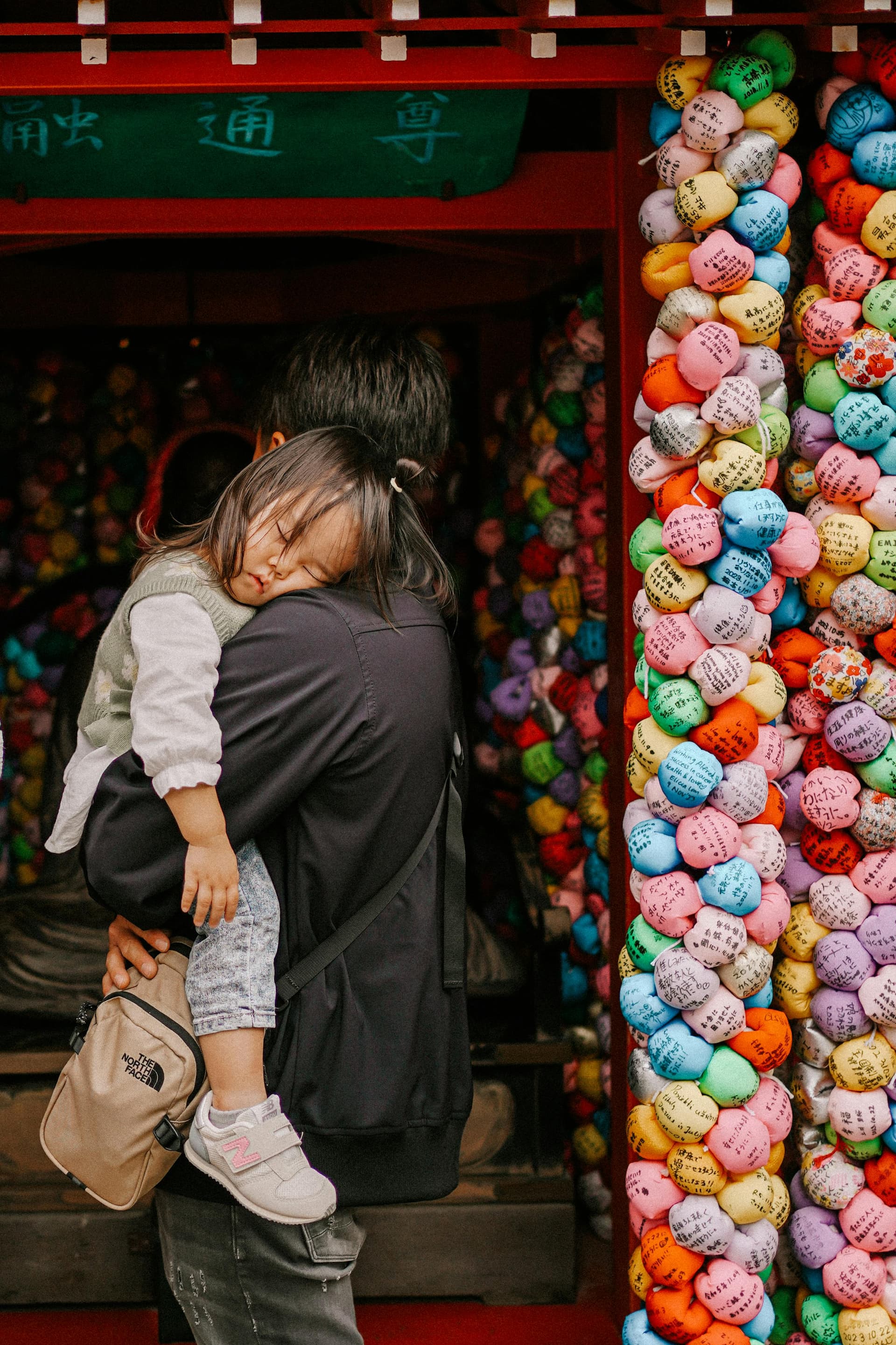 Parent and child at a temple entrance with colorful wishing balls