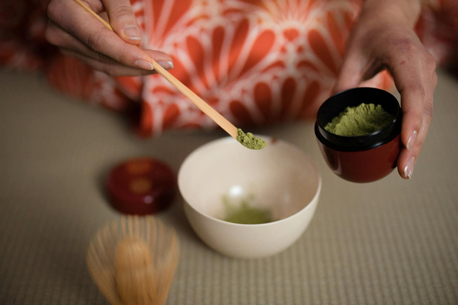 Woman preparing matcha in a traditional Japanese tea ceremony with bowl and whisk