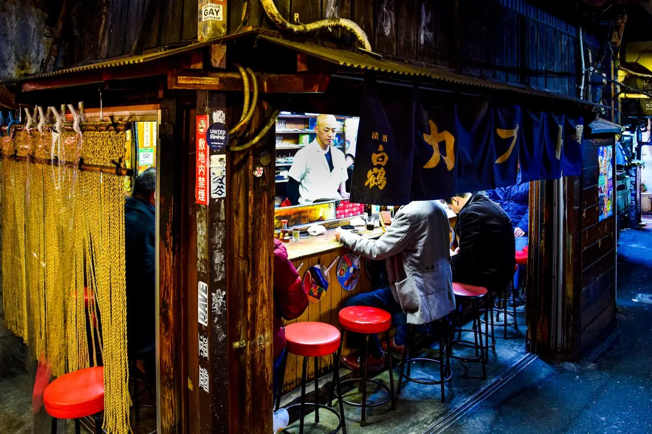 Diners on red stools at the Kabuto counter in Omoide Yokocho, Shinjuku