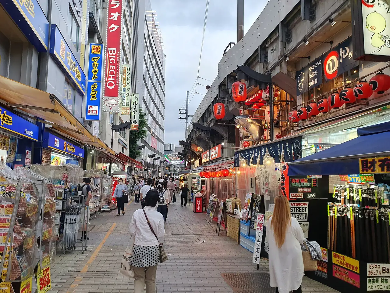 Shoppers walking past stalls and lanterns on the Ameyoko market street in Ueno