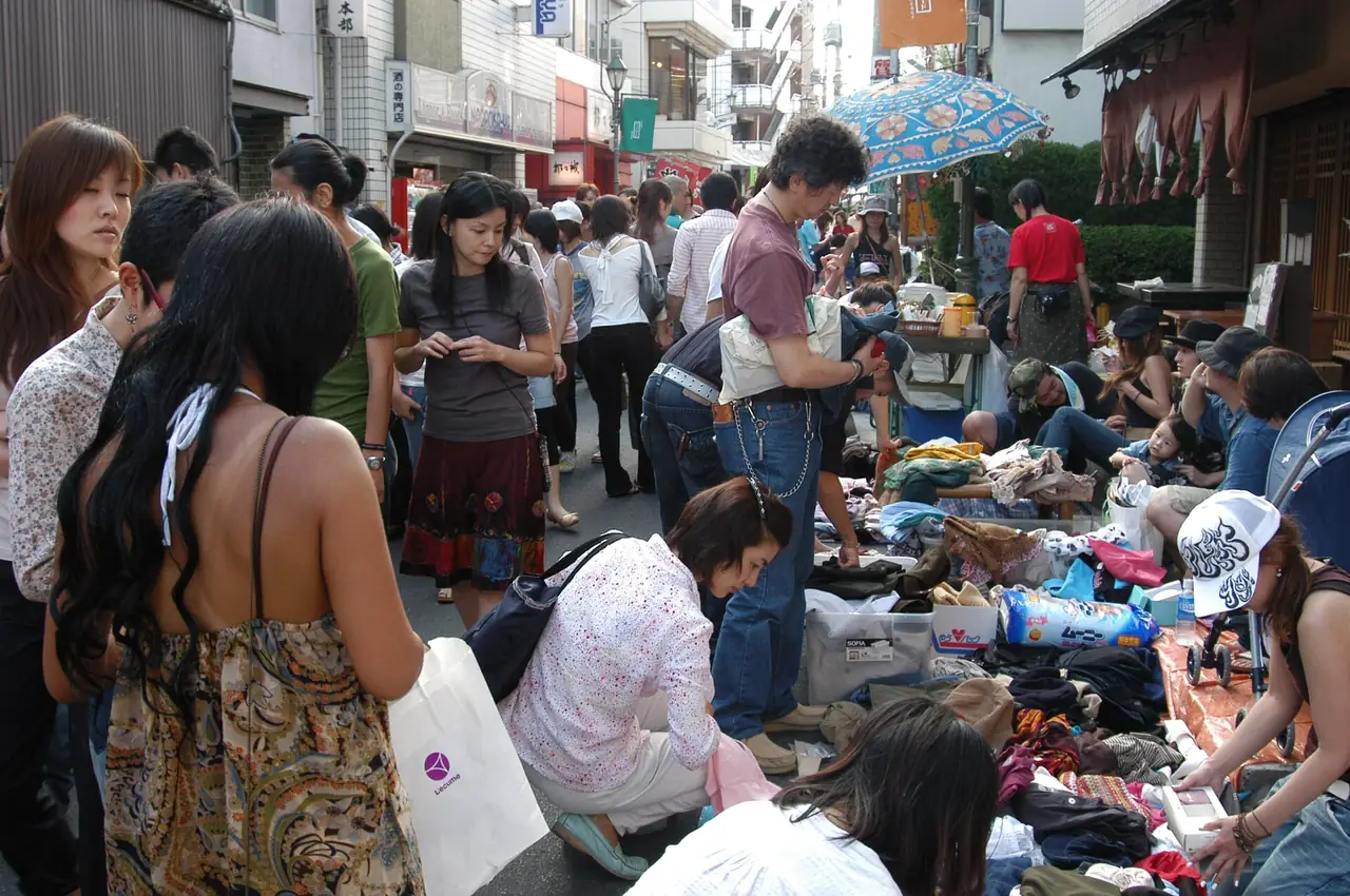 Shoppers sorting through secondhand clothes laid out on a Shimokitazawa street