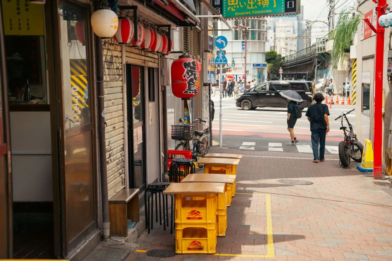 Beer crate tables set out under lanterns at an Omoide Yokocho entrance before evening