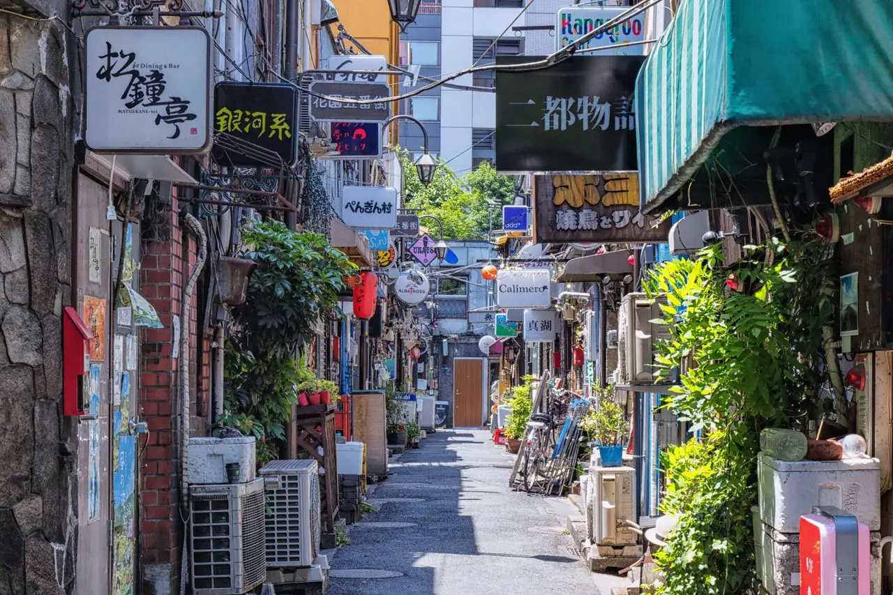 Bar signs stacked along a quiet Golden Gai alley in Shinjuku by day