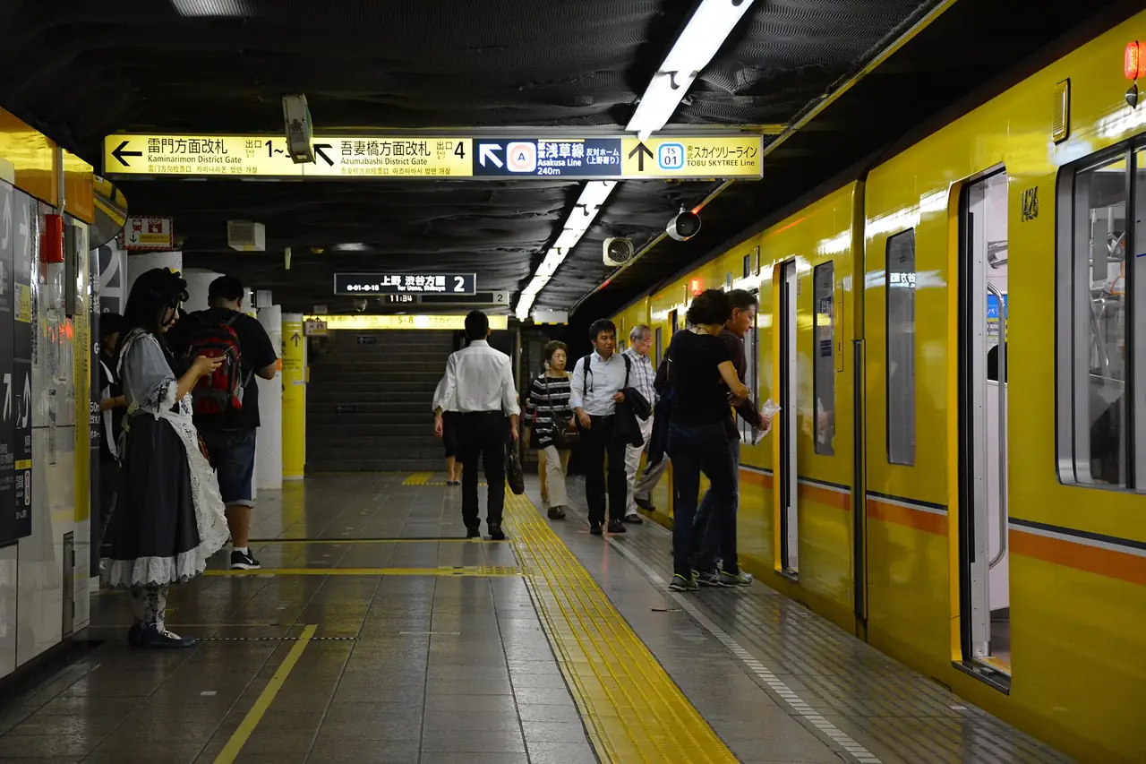 Passengers boarding a yellow Ginza Line subway train at an underground Tokyo platform