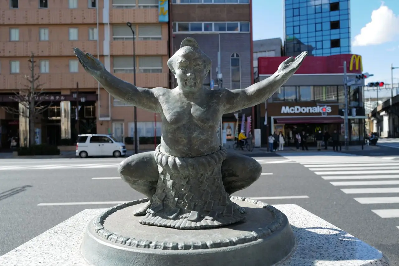 Bronze statue of a crouching sumo wrestler on a street corner near Ryogoku Station