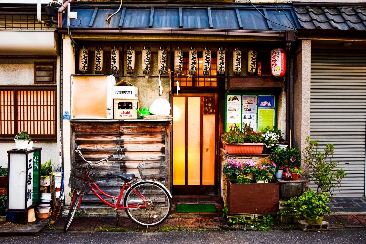 Traditional wooden shopfront with paper lanterns and a red bicycle on a quiet backstreet