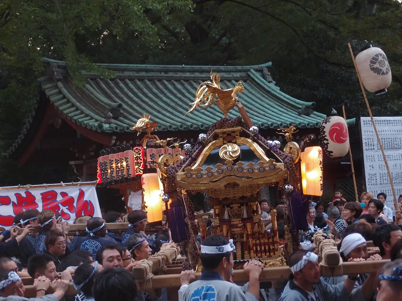 Bearers in happi coats carrying a golden mikoshi through Nezu Shrine at festival time