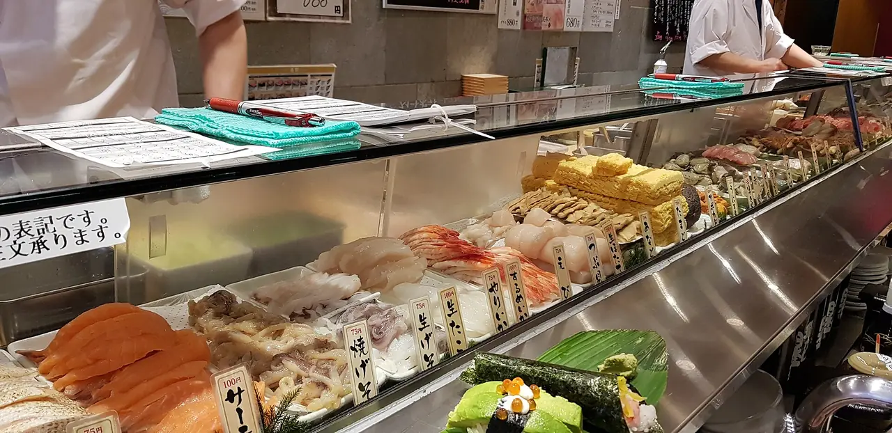 Sushi chefs behind a counter of fresh fish at Uogashi standing sushi bar in Shibuya