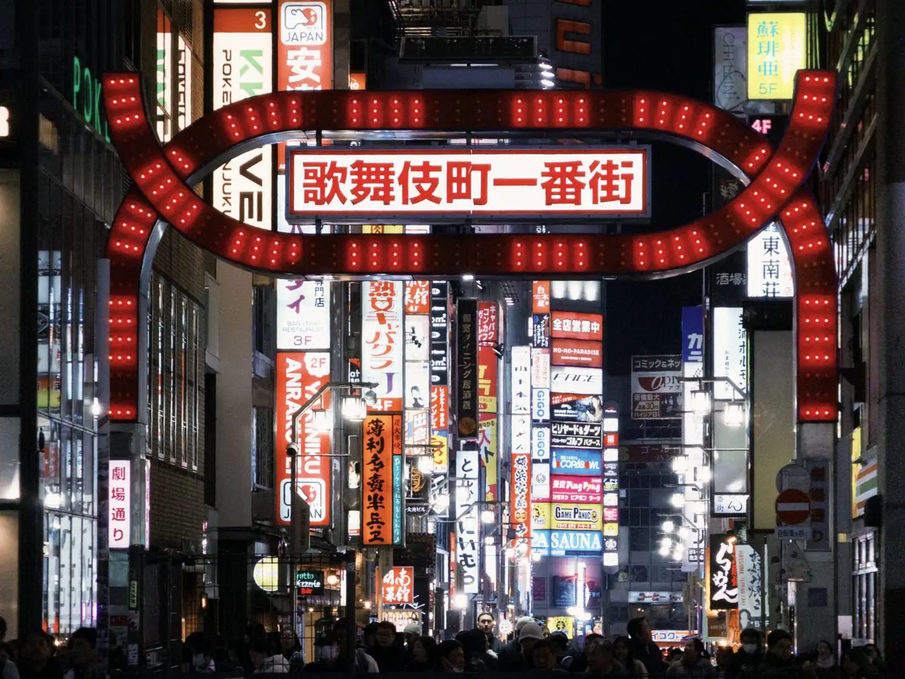 Red neon Kabukicho Ichibangai gate over a busy Shinjuku street at night