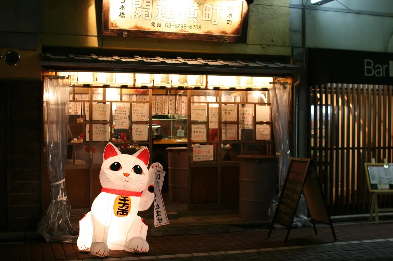 Lucky cat figure outside a standing bar near Kanda Station with menu slips in the window