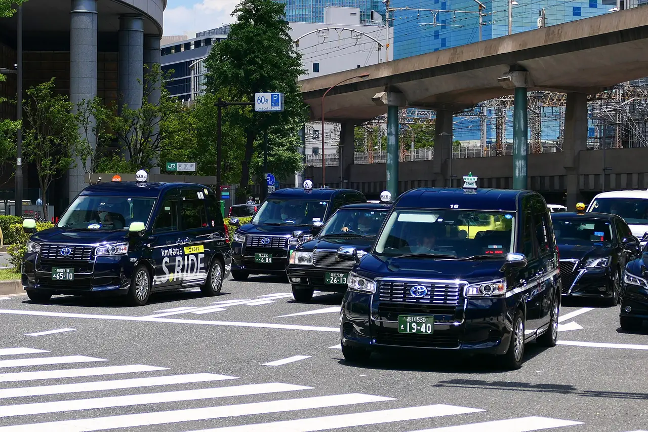 Dark blue JPN Taxi cabs on the road beside Tokyo Station in Marunouchi
