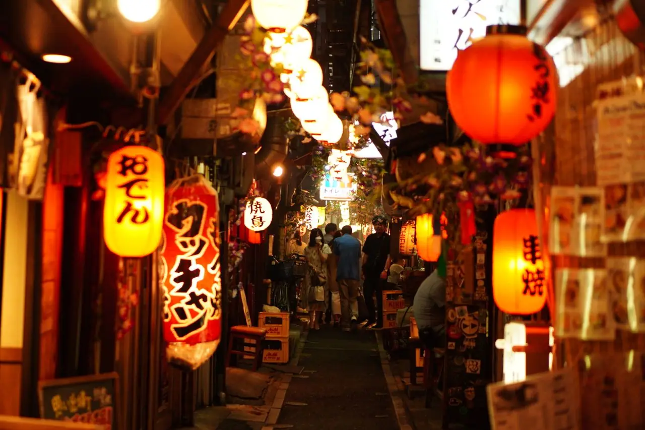 Paper lanterns glowing over a narrow alley of small eateries in Shinjuku at night