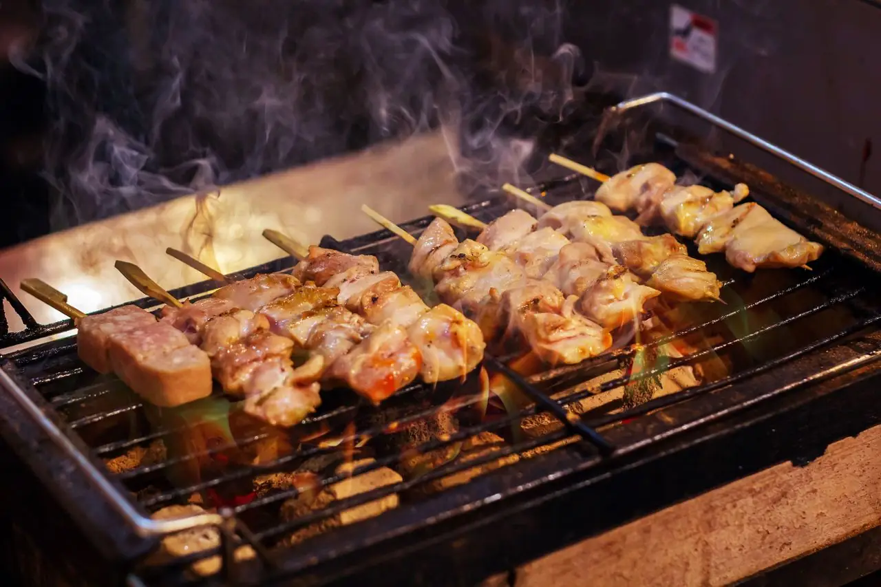Chicken yakitori skewers sizzling on a smoky grill