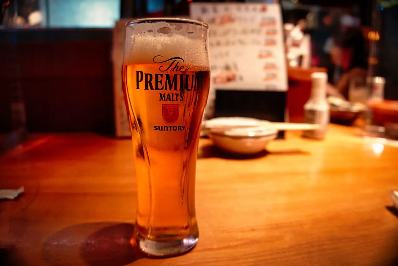 A glass of draft Premium Malts beer on a wooden bar counter in Tokyo