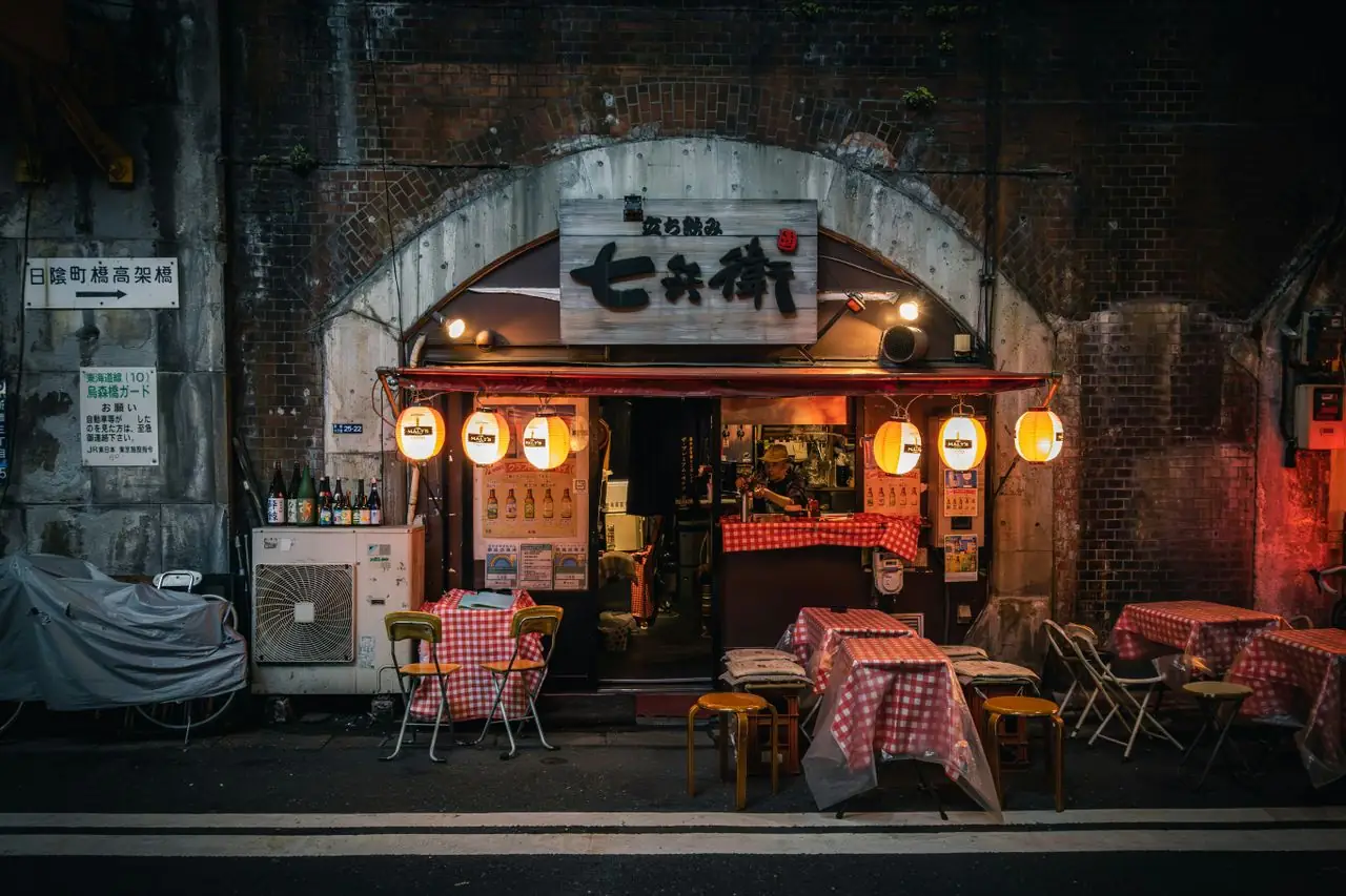 Lantern-lit standing bar with outdoor tables under the brick railway arches in Shinbashi