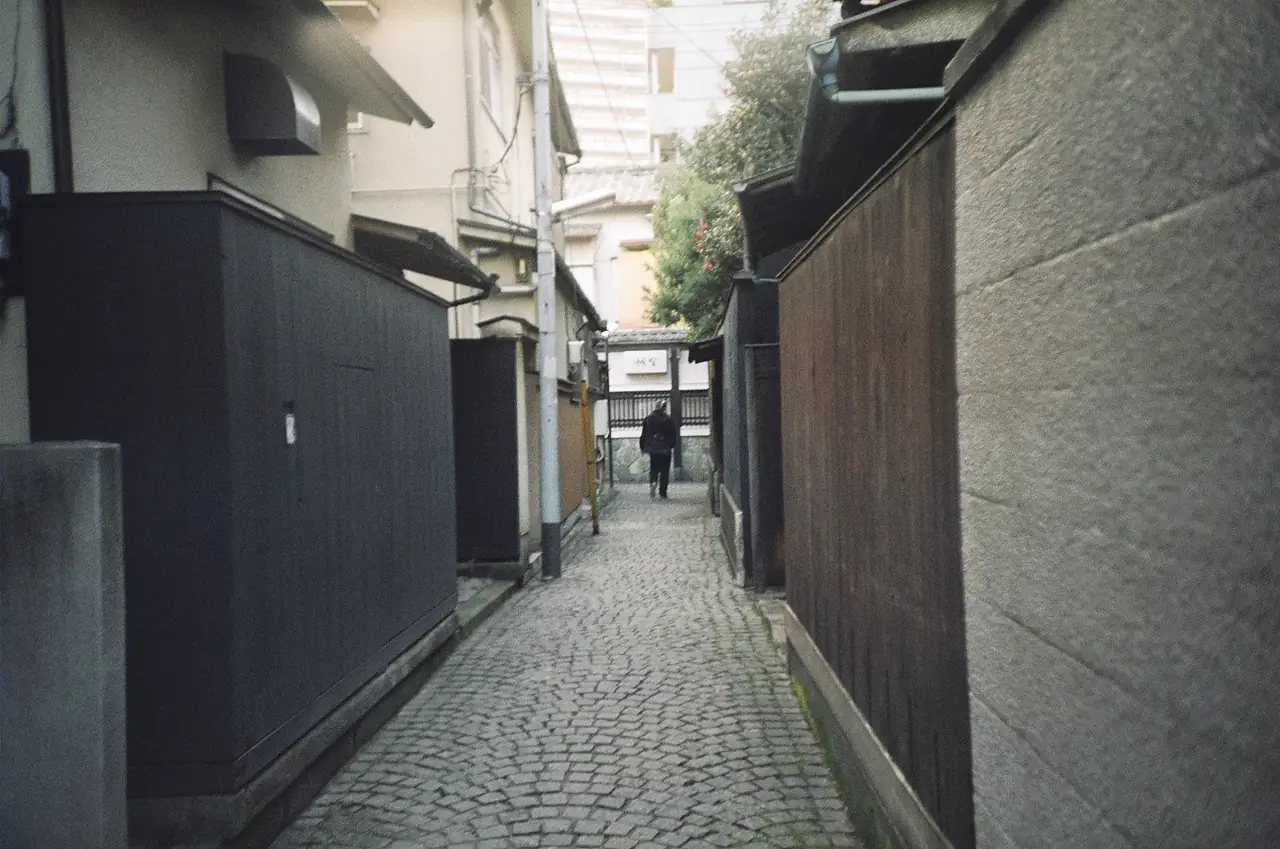 A narrow cobblestone alley lined with dark wooden walls in Kagurazaka, Tokyo