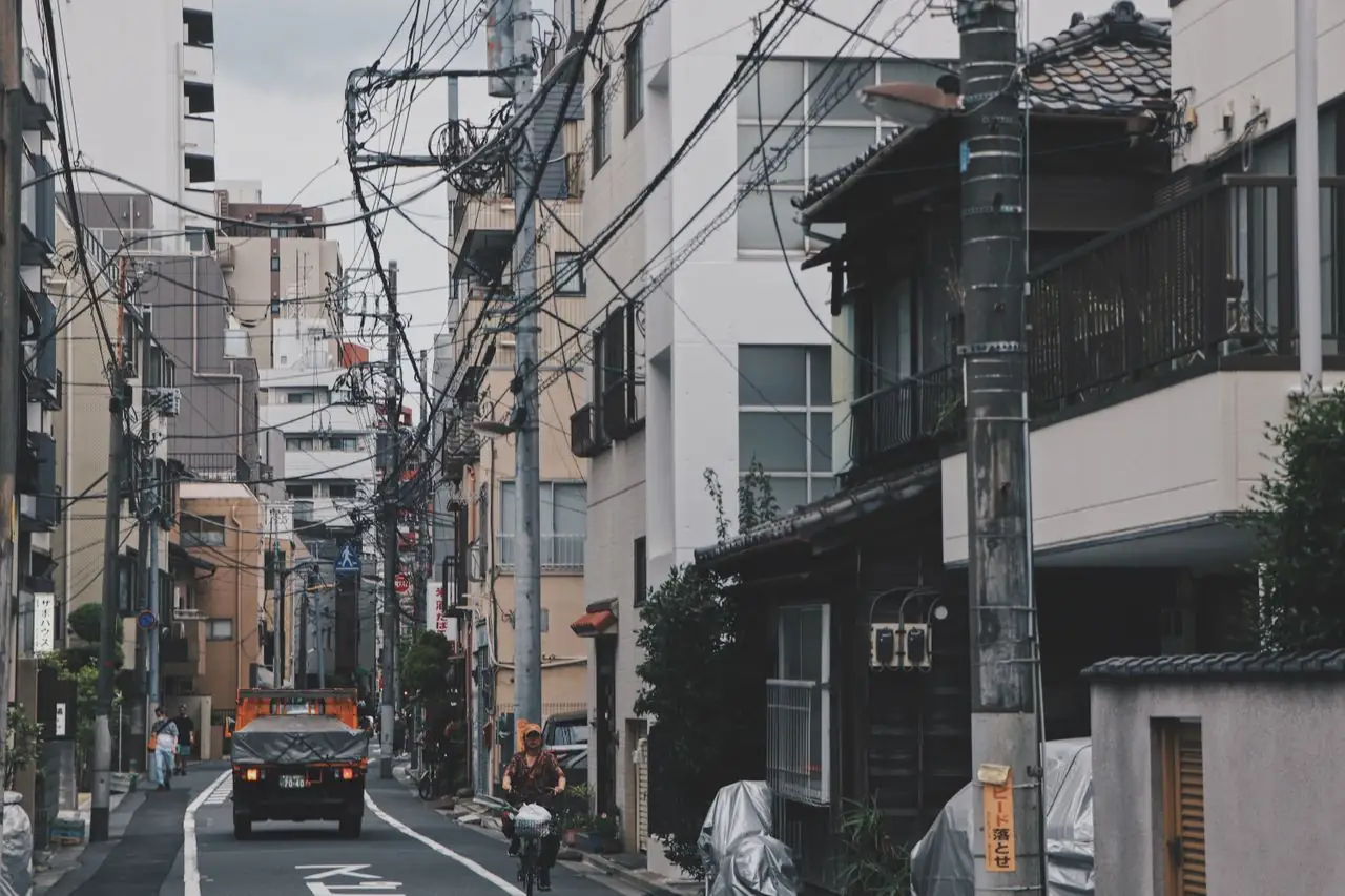 An old tiled-roof wooden house between apartment blocks on a residential Tokyo street