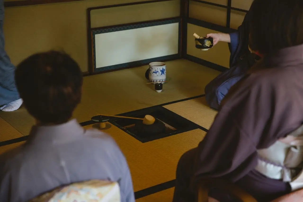 Guests in kimono seated on tatami as tea is served in a Japanese tea room