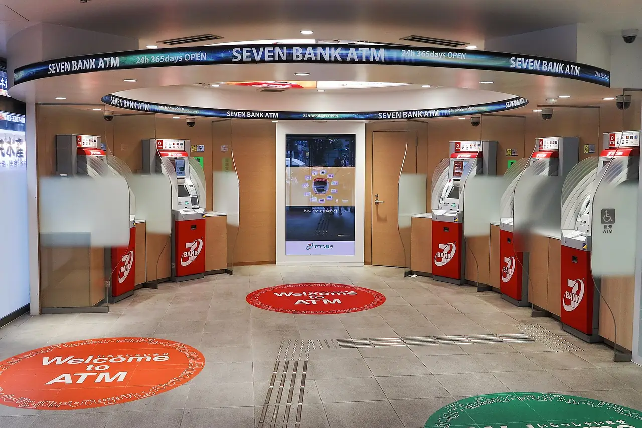 A row of Seven Bank ATMs under a sign saying open 24 hours, 365 days