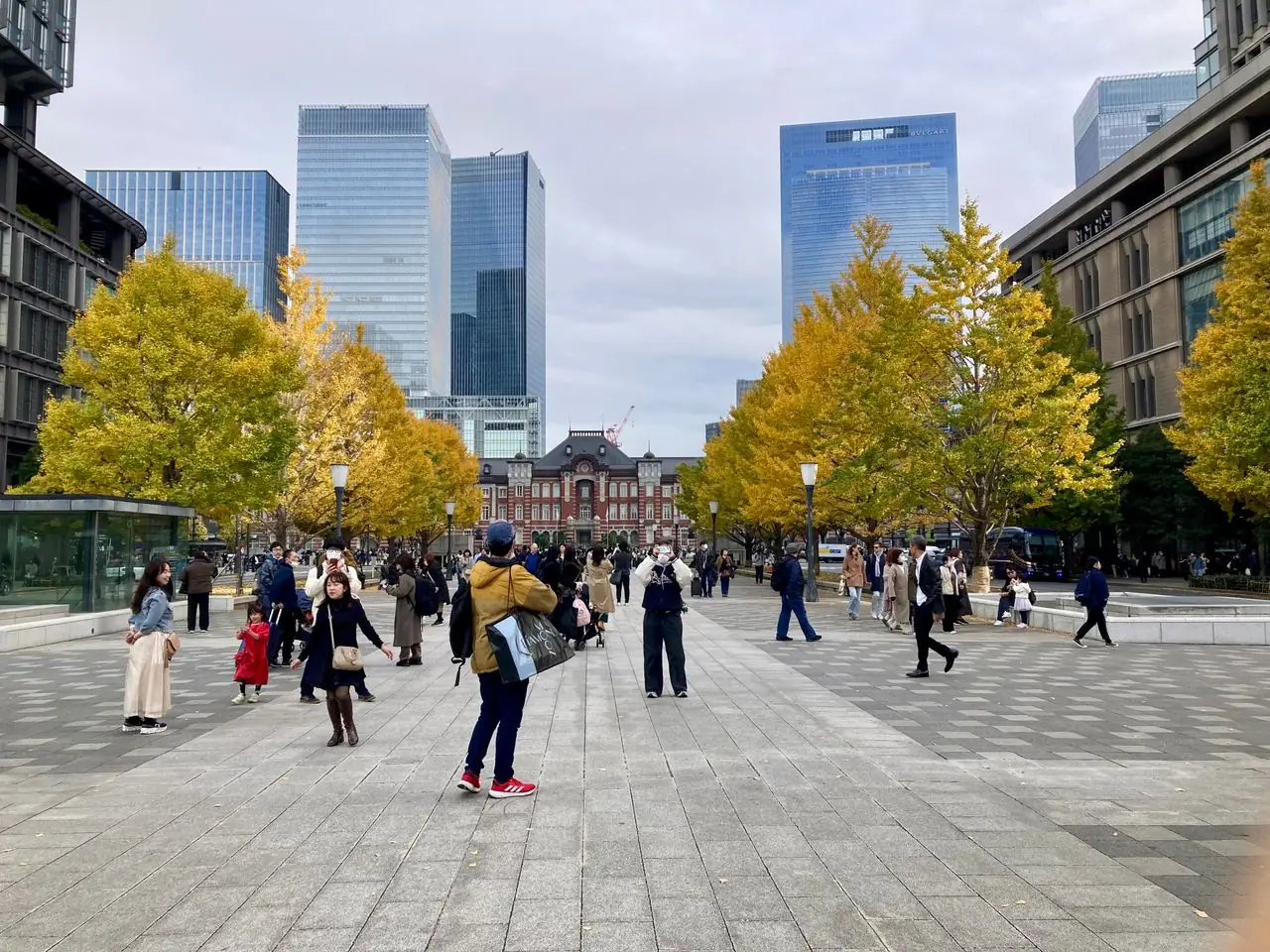 Autumn ginkgo trees along Gyoko-dori with Tokyo Station's red brick facade at the far end