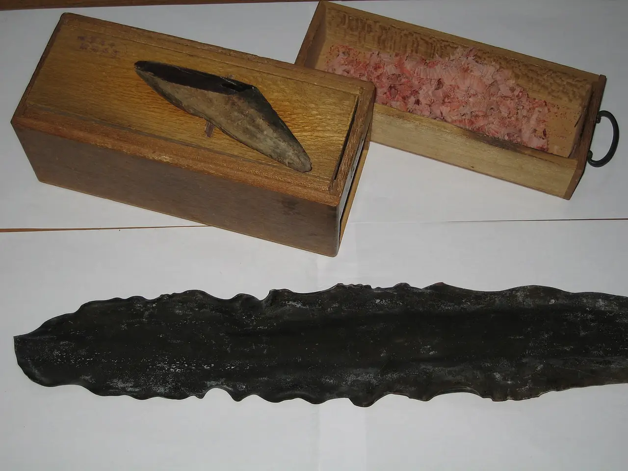 A block of katsuobushi on a wooden shaving box beside a sheet of dried kombu