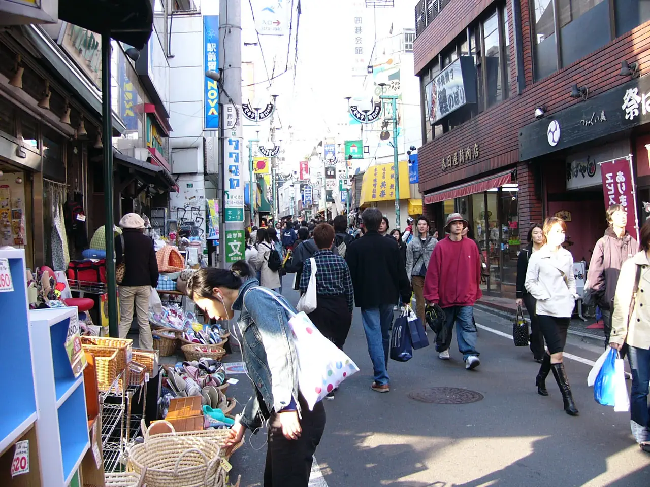 Shoppers and sidewalk displays along a busy Shimokitazawa shopping street