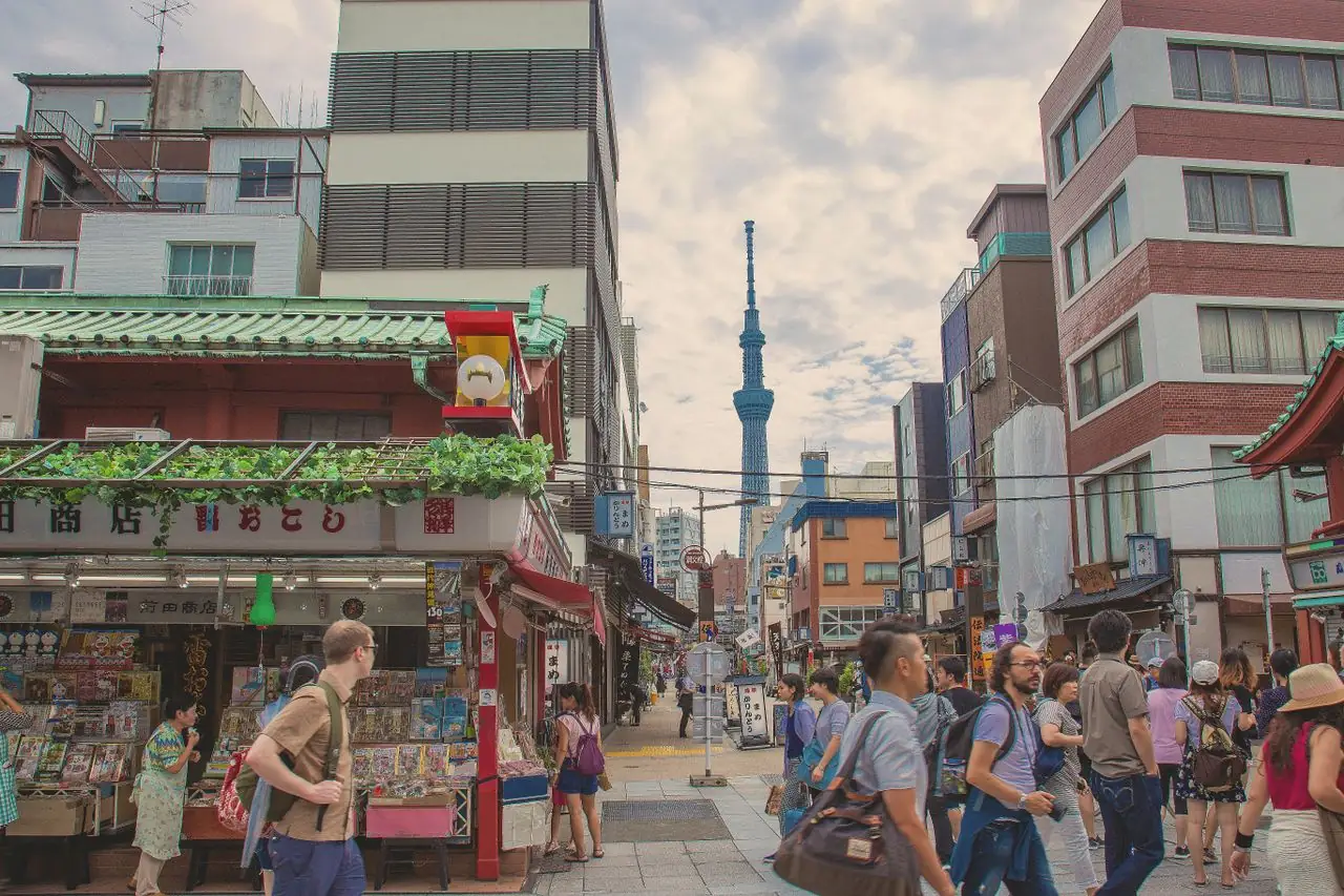 Visitors walking a shopping street in Asakusa with Tokyo Skytree in the distance
